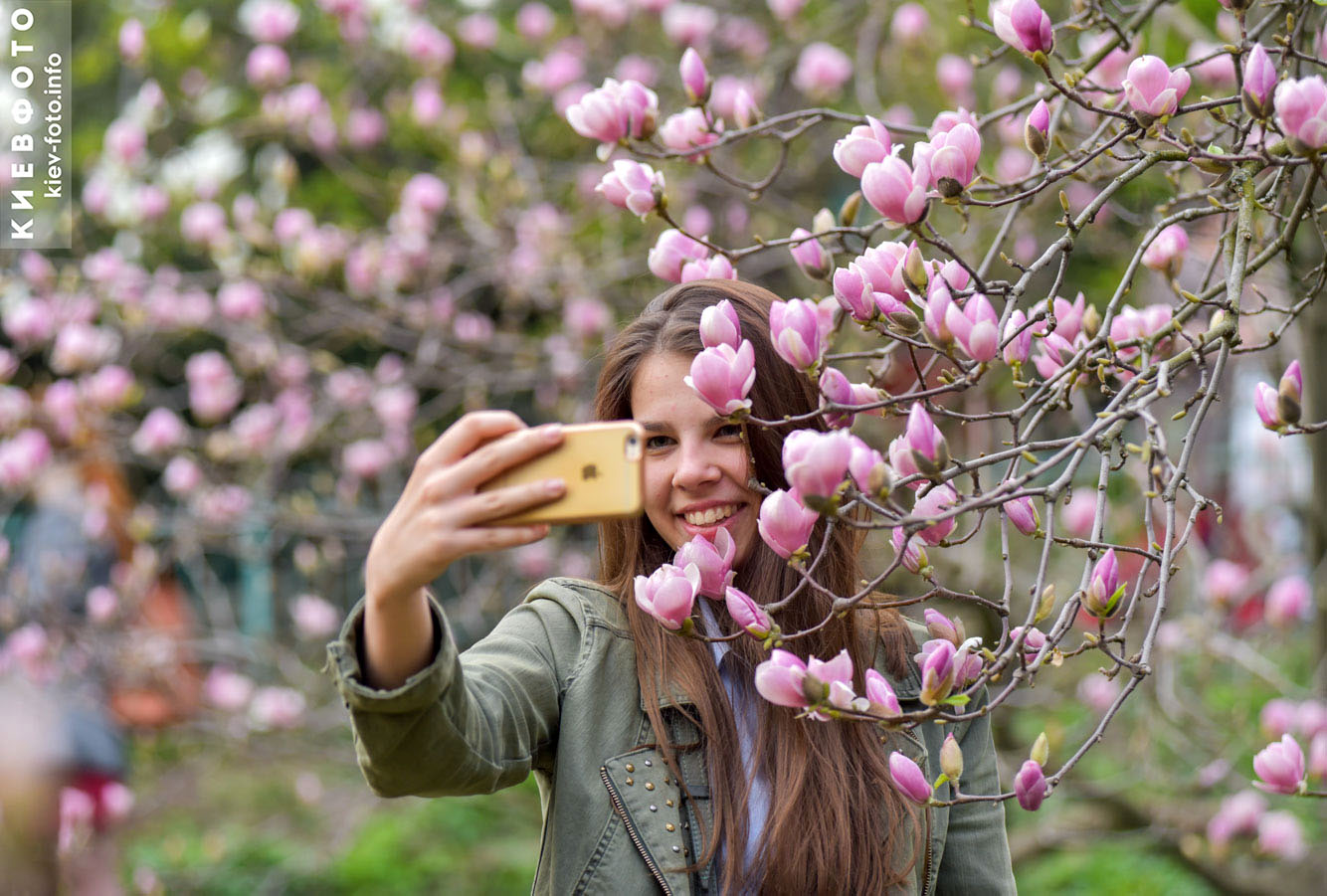 люди фотографируются с цветками магнолии